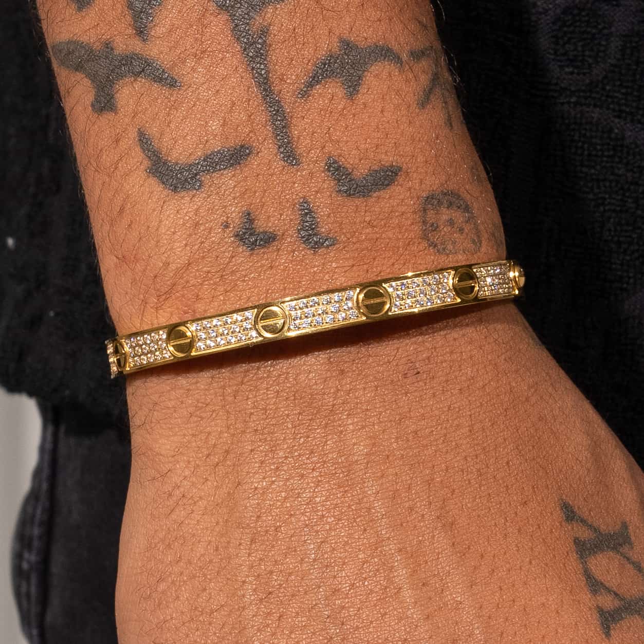 Gold iced band bracelet with nail-like designs, inspired by Cartier, shown on wrist.